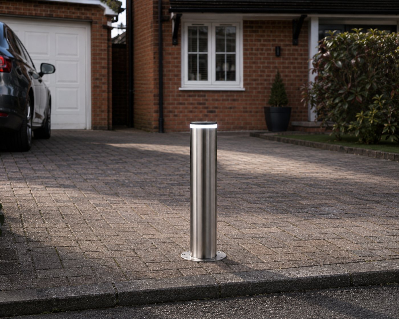 One bollard raised in the middle of a single-car driveway opening.